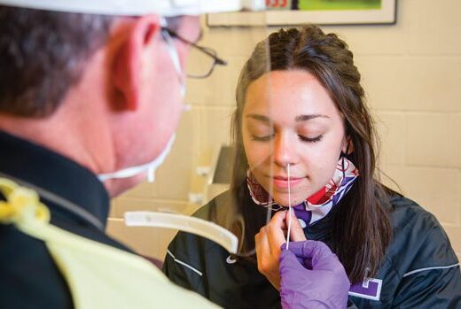 Garry Killgore, Linfield's athletic director, performing COVID-19 test on student-athlete