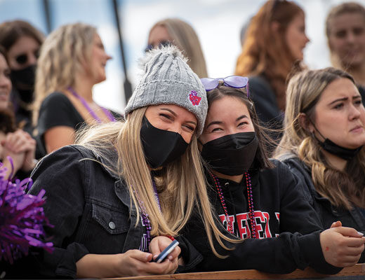 a group of students cheering on the Wildcats at Linfield's Homecoming game