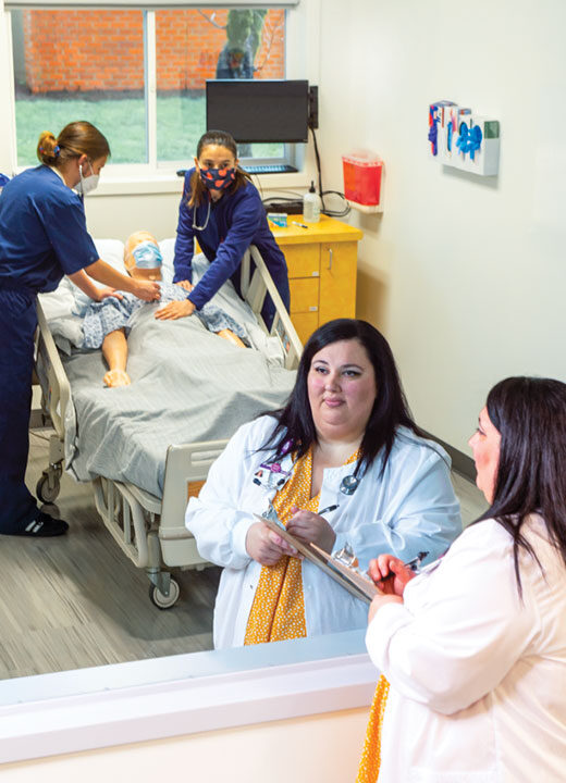 Kiki Fornero, assistant professor of nursing, evaluating two students in a simulation lab