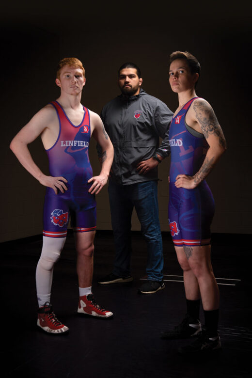 Linfield wrestlers Abram Nelson '24 and Carissa Love '23 with head coach Chad Hanke in the back