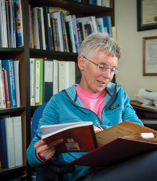 Laura Kenow looking through a scrapbook in her office