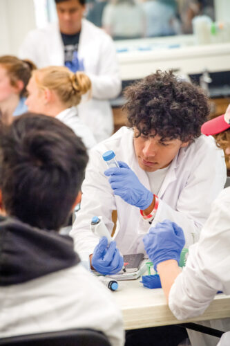Group of students inspecting dirt samples in test tubes.