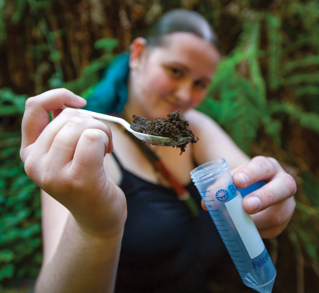 Student holding plastic spoon full of dirt.