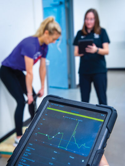 Linfield grad student working with student-athlete with new lab equipment.