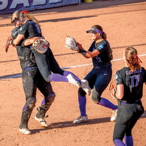 Four Wildcat softball players celebrating.