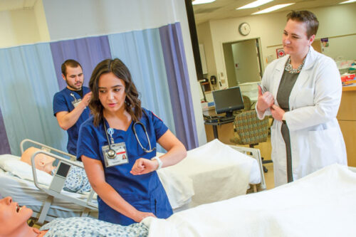 Jordan Ferris with two nursing students practicing on manikins.