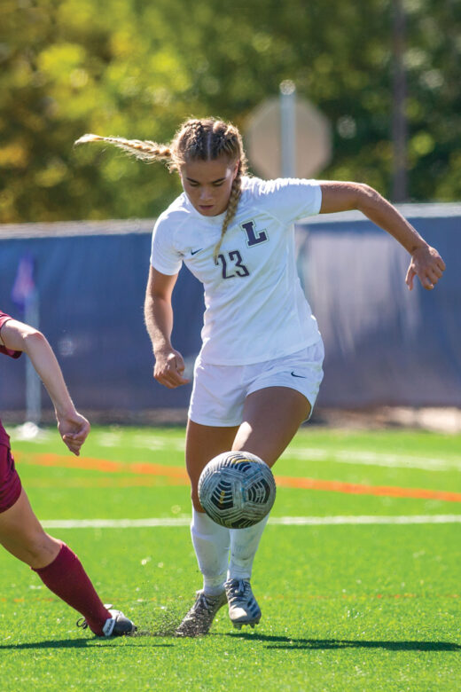 Linfield women's player dribbling soccer ball.