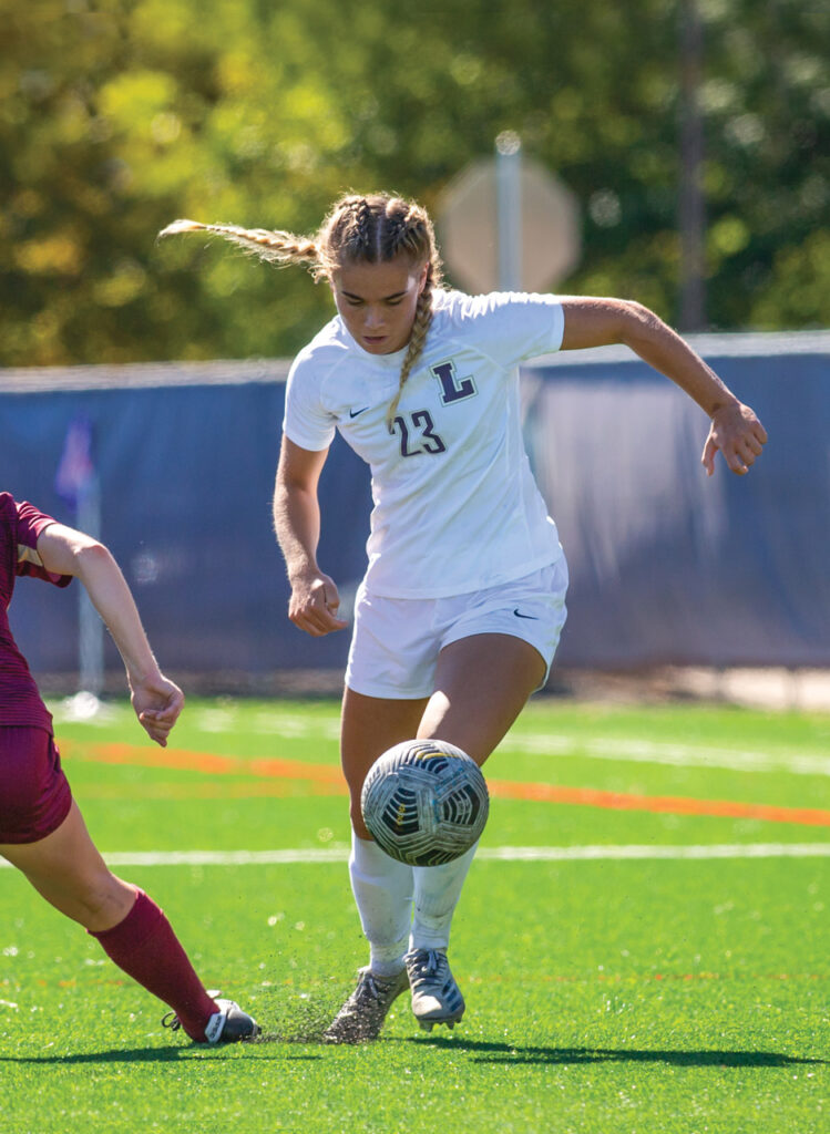 Linfield women's player dribbling soccer ball.