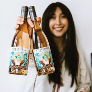 Stephanie Juanillo '21 holding two bottles of wine with her label art.