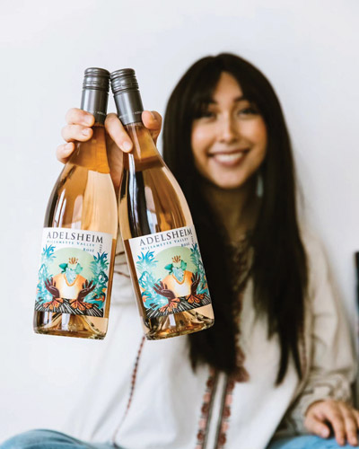 Stephanie Juanillo '21 holding two bottles of wine with her label art.