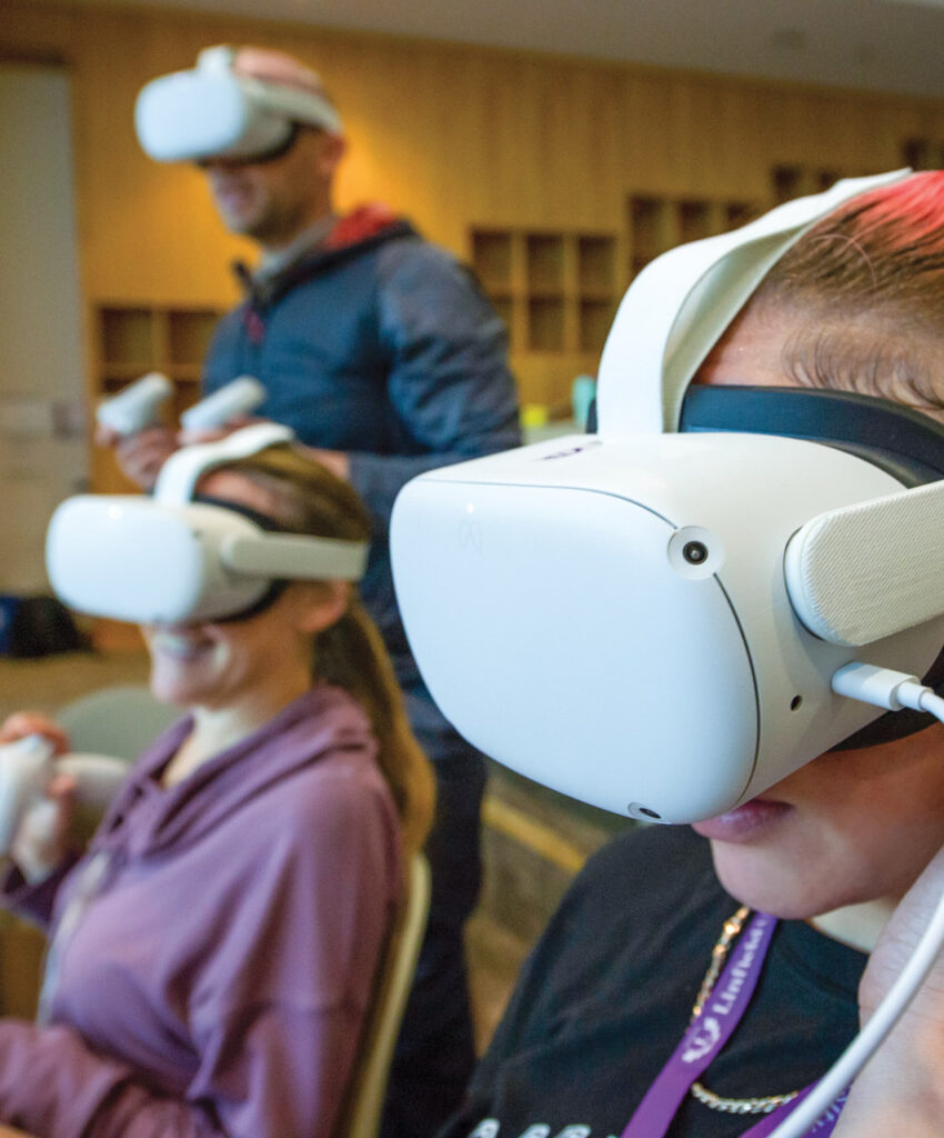 Three Linfield students wearing virtual reality Oculus headsets.