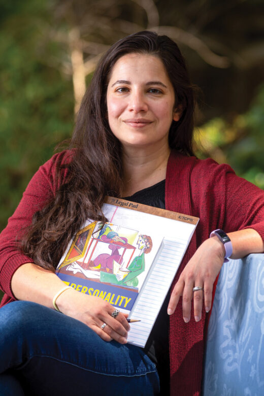 Yanna Weisberg holding a book and notepad sitting on a bench.