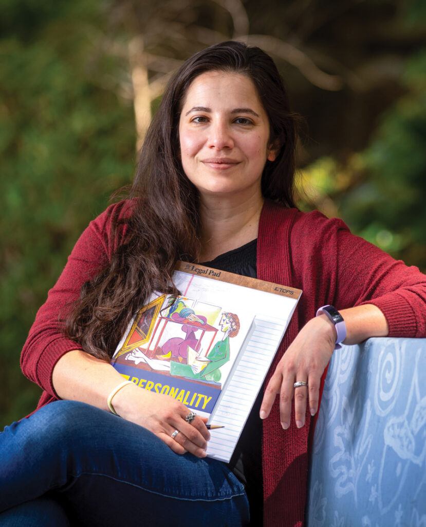 Yanna Weisberg holding a book and notepad sitting on a bench.