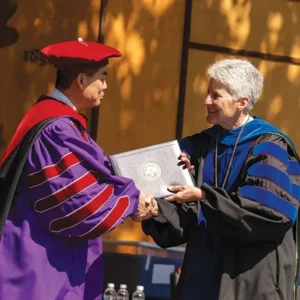 Interim President Becky Johnson hands Shawn Chen an honorary degree at the 2024 commencement.