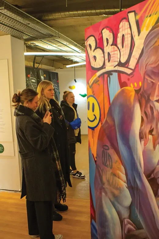 Students view an art exhibit about the history of sports in Paris, France.