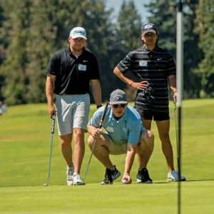 three golfers look toward the pin at the golf course.