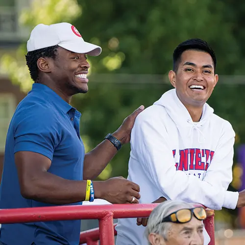 Two students smiling while watching the football game.