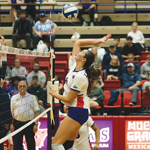a Linfield volleyball player jumping up to hit the ball.