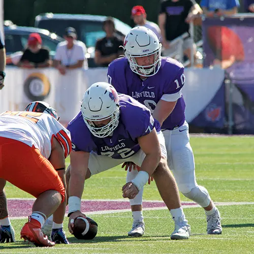 the Linfield quarterback taking a snap during the Homecoming football game.