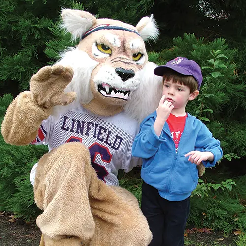 angry looking Wildcat mascot posing by a child