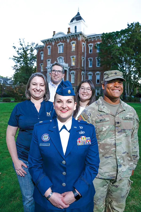 Stacey Prescott is joined by fellow veterans or military-affiliated students Leanne Babcock, Divenson Willis, Azia Salbego and Evan Salbego for a photo in front of Pioneer Hall.